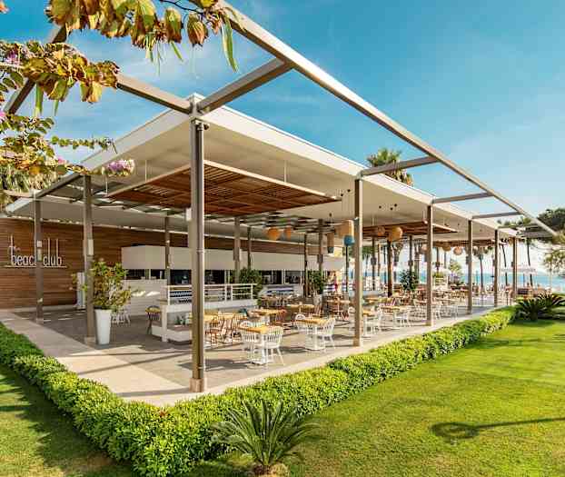 En moderne udendørsrestaurant med udendørs servering omgivet af grønne områder. (AI-genereret tekst)