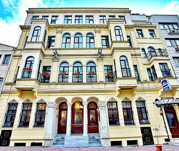 Facaden af en ældre bygning med altaner og dekorerede vinduer. (AI-genereret tekst)