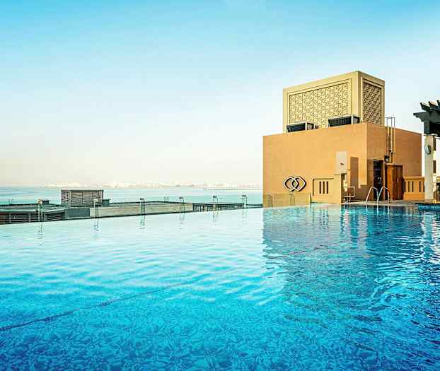 En infinitypool med udsigt over havet og en bygning. (AI-genereret tekst)