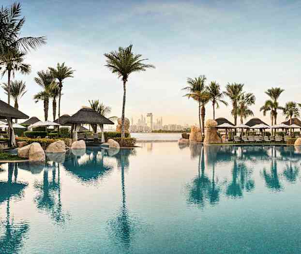 Udsigt over en pool foran resortet med palmer og parasoller. (AI-genereret tekst)