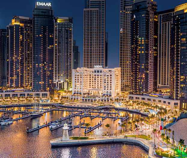 En bysilhuet om aftenen med oplyste høje bygninger og en marina i forgrunden. (AI-genereret tekst)