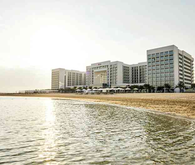 Et stort hotelkompleks ved en strand med havet i forgrunden. (AI-genereret tekst)