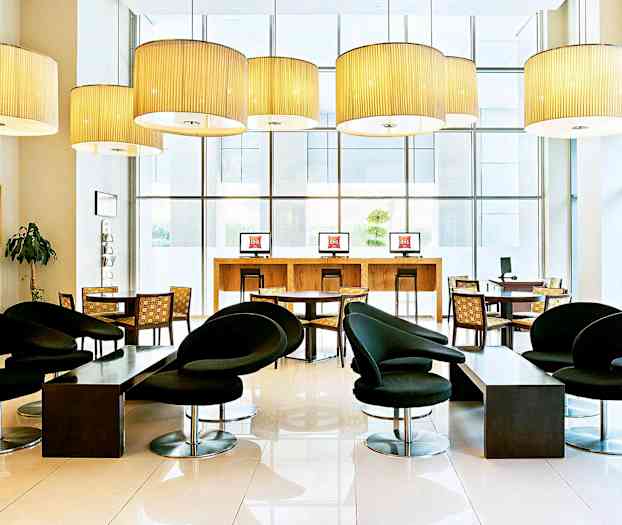 Et moderne møbleret hotellobbyområde med sorte stole, borde og computere. (AI-genereret tekst)