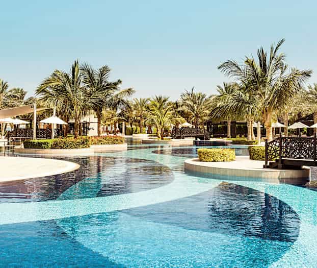 En ferieresortspool med palmer og siddeområder i baggrunden. (AI-genereret tekst)