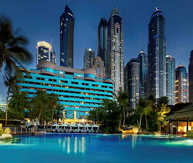 Hotel med blå facade ved en pool med højhuse i baggrunden. (AI-genereret tekst)