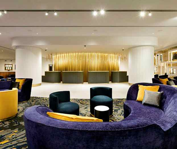 Hotellets reception med moderne møbler og varm belysning. (AI-genereret tekst)