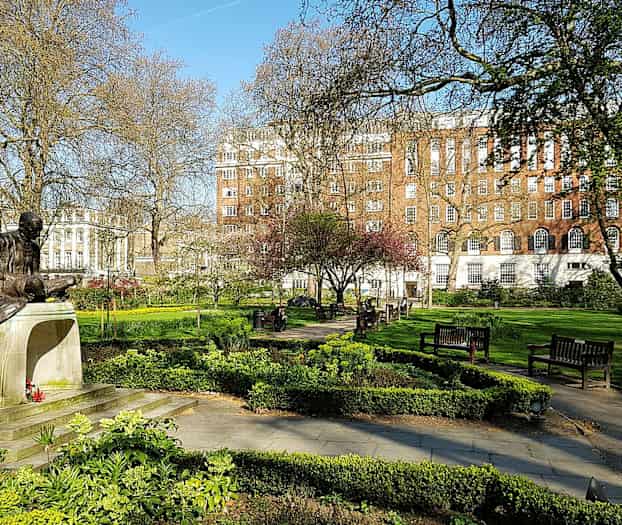 Statue i en park med grønne områder og bænke. (AI-genereret tekst)