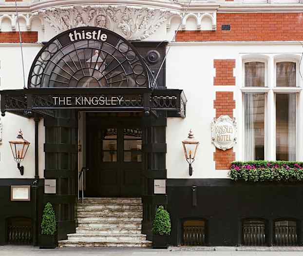 Hotelindgang med trapper, skilt og blomster. (AI-genereret tekst)