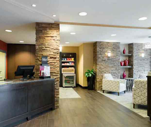 Reception i et hotel med elegant indretning, herunder stenbeklædte vægge og behagelige siddeområder. (AI-genereret tekst)