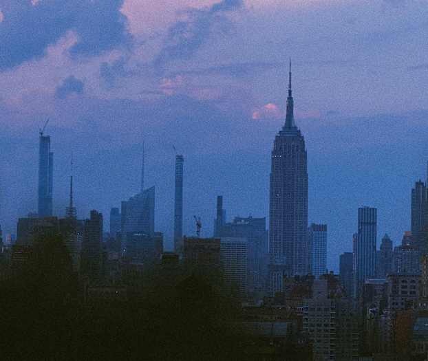 Udsigt over en bys skyline i skumringen med flere skyskrabere mod en farverig himmel. (AI-genereret tekst)