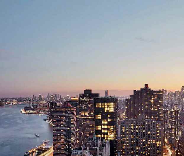 Udsigt over en by med flere højhuse og en flod i forgrunden ved solnedgang. (AI-genereret tekst)