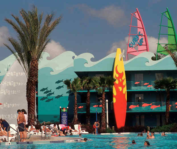 En pool omgivet af liggestole og mennesker. Bagved er en bygning med farverig dekoration af bølger, fisk og et stort surfbræt. (AI-genereret tekst)