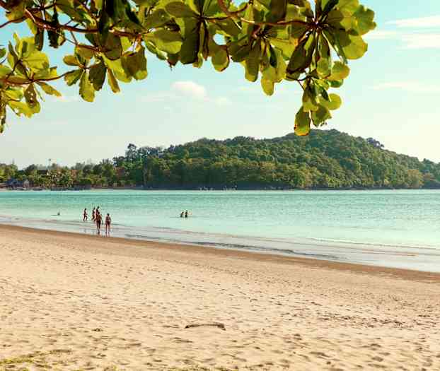 En sandstrand med mennesker, havet og en skovklædt ø i baggrunden. (AI-genereret tekst)