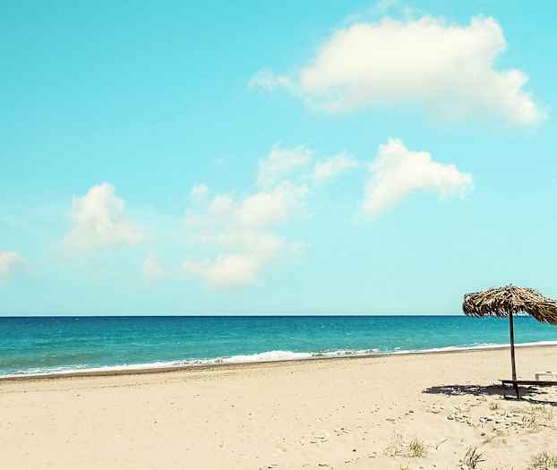 En sandstrand med parasol, havet i baggrunden. (AI-genereret tekst)