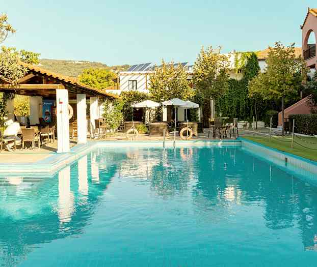 Poolområde med omkringliggende bygninger og beplantning. (AI-genereret tekst)