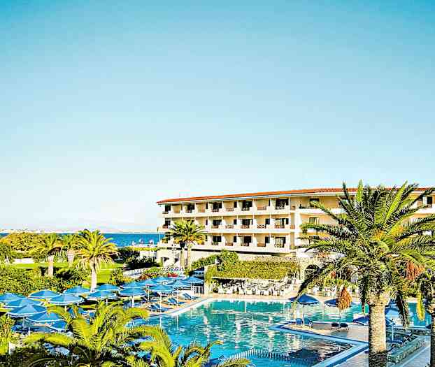 Hotelbygning med flere etager omgivet af palmer og en stor pool. (AI-genereret tekst)