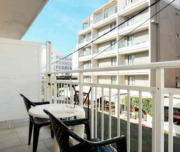 En altan med to stole og et bord, udsigt til bygninger. (AI-genereret tekst)