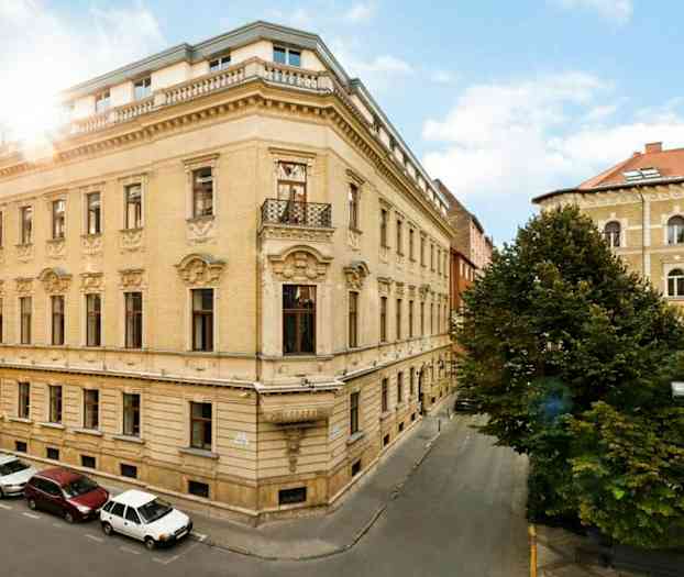 Gadelygterne står ved et grønt område omgivet af høje bygninger. (AI-genereret tekst)