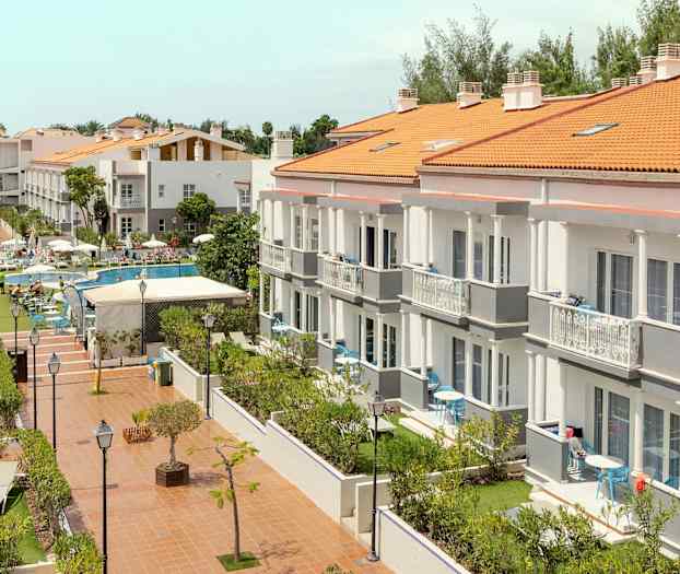 Et hotelkompleks med flere bygninger, poolområde og have. (AI-genereret tekst)