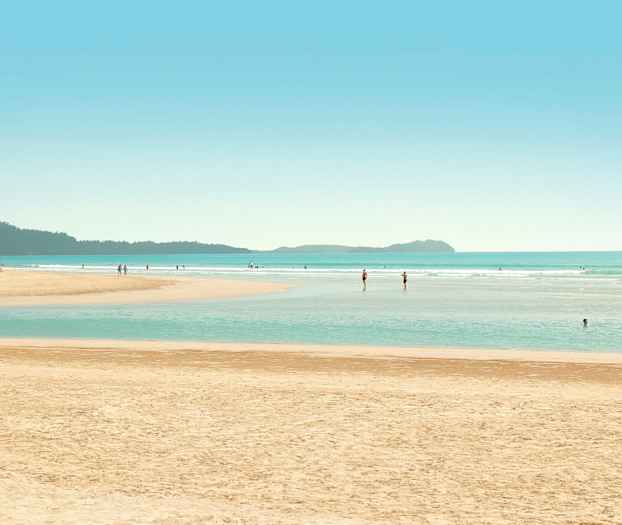 En strand med mennesker, der svømmer og går i vandet. (AI-genereret tekst)