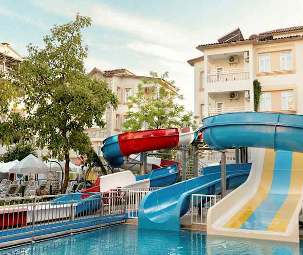 Billede af en vandpark med vandrutsjebaner og bygninger i baggrunden. (AI-genereret tekst)