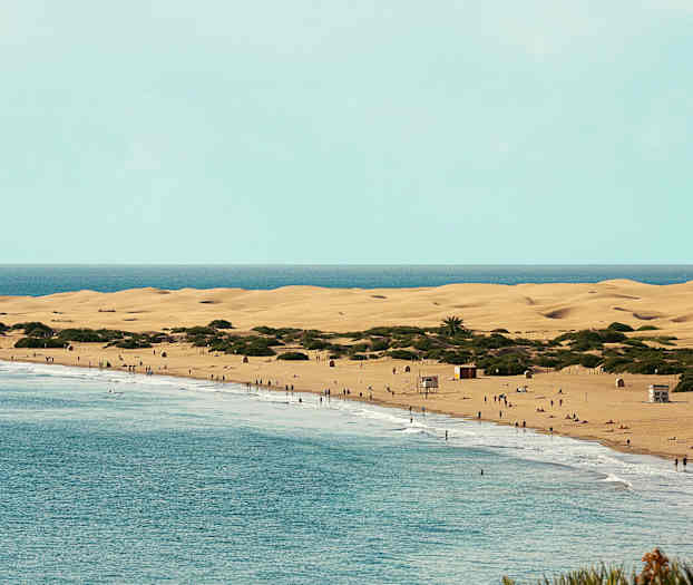 En strand med sandklitter og mennesker ved vandet. (AI-genereret tekst)