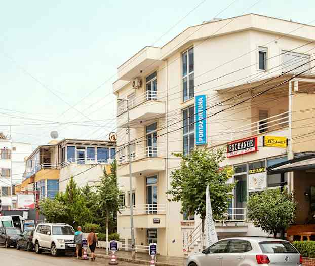 Gade med parkerede biler og bygninger med skilte. (AI-genereret tekst)