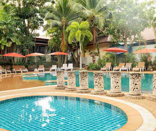 En udendørs swimmingpool omgivet af palmer og liggestole med parasoller. (AI-genereret tekst)