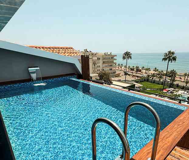 En lille pool på et tag med udsigt over havet og et bylandskab. (AI-genereret tekst)