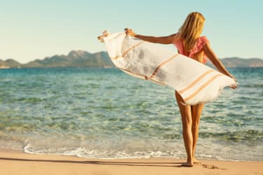 kvinde alene på stranden med håndklæde