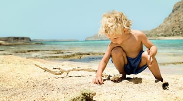 Dreng leger på stranden på Kreta