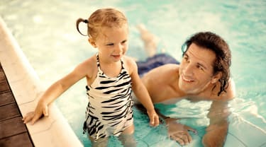 Far og datter svømmer sammen i basseng
