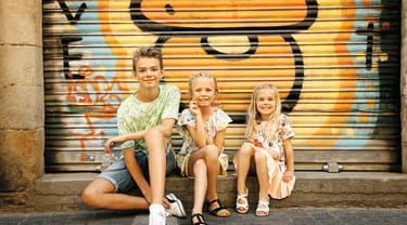 Tre børn sidder ved en graffitivæg i barcelona