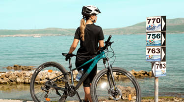 kvindelig cyklist ser ud over vandet