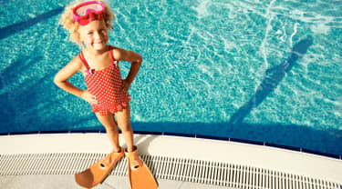 pige med svømmebriller- og fødder står ved pool