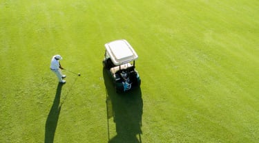 Golfbil og golfspiller på en fairway