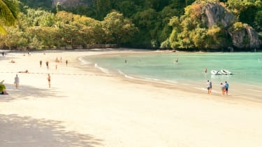 Strand med mennesker på badeferie i Thailand