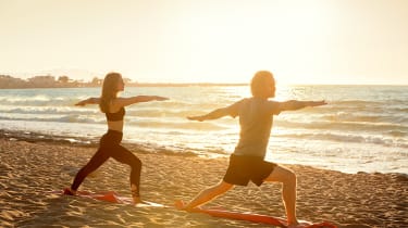 Kvinde og mand laver yoga på stranden