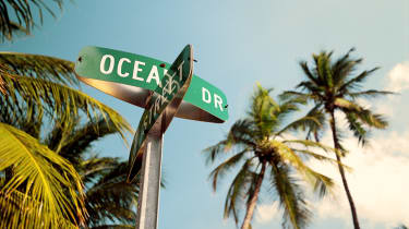Gadeskilte ved krydset mellem Ocean Drive og 7th street i Miami Beach med palmer i baggrunden