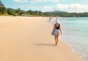 kvinde går på stranden i thailand og nydr solen