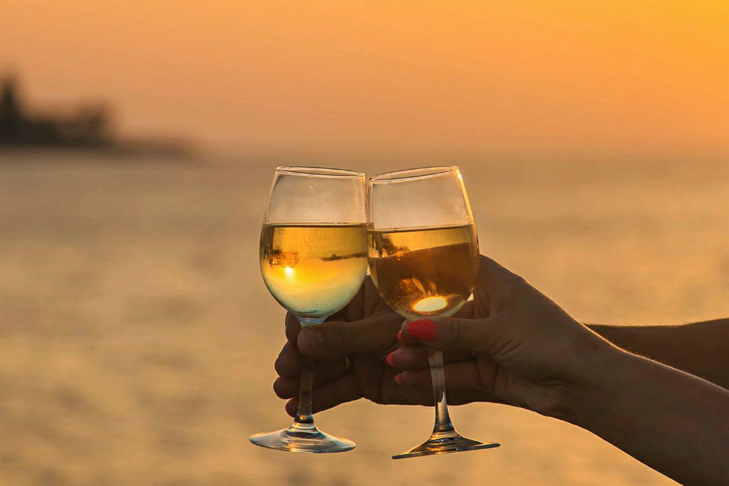 To vinglas skåler foran en solnedgang ved havet. (AI-genereret tekst)