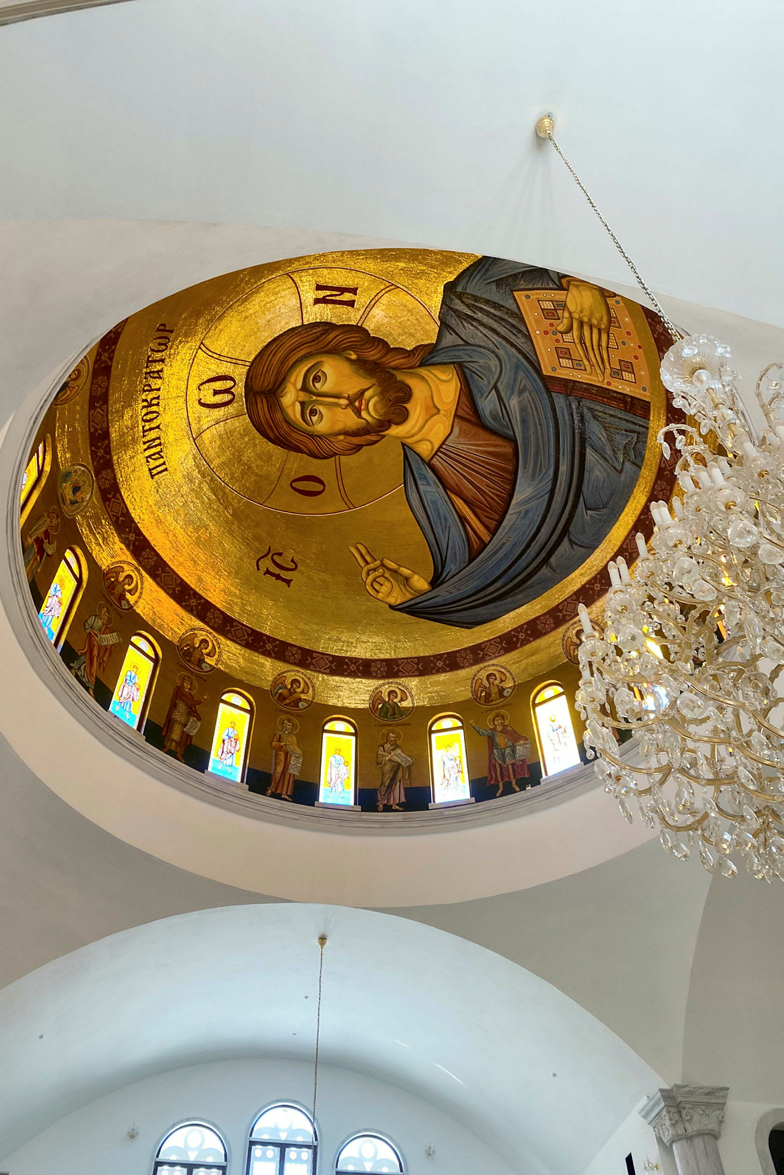 Interiør af en kirke med et dekoreret loft i gylden mosaik og en lysekrone. (AI-genereret tekst)