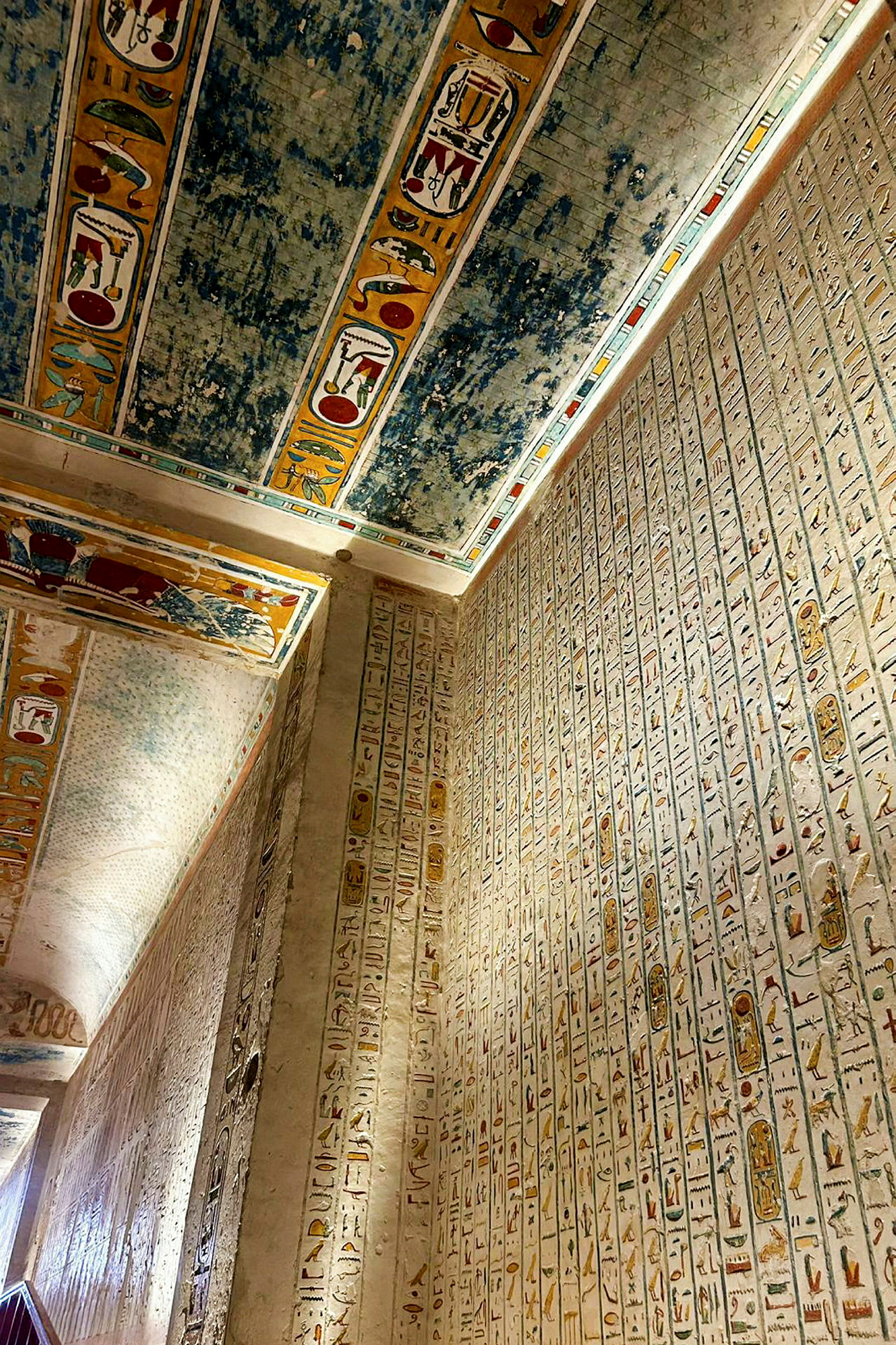 En væg dækket med hieroglyffer og et loft med farverige dekorationer i en gammel egyptisk struktur. (AI-genereret tekst)