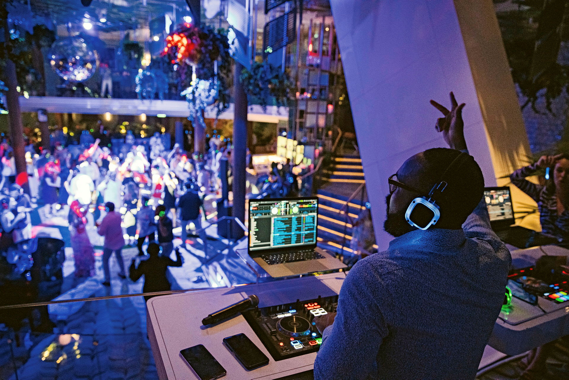 En DJ står ved sit mixerbord og spiller musik på en natklub, hvor folk danser under blinkende lys. (AI-genereret tekst)
