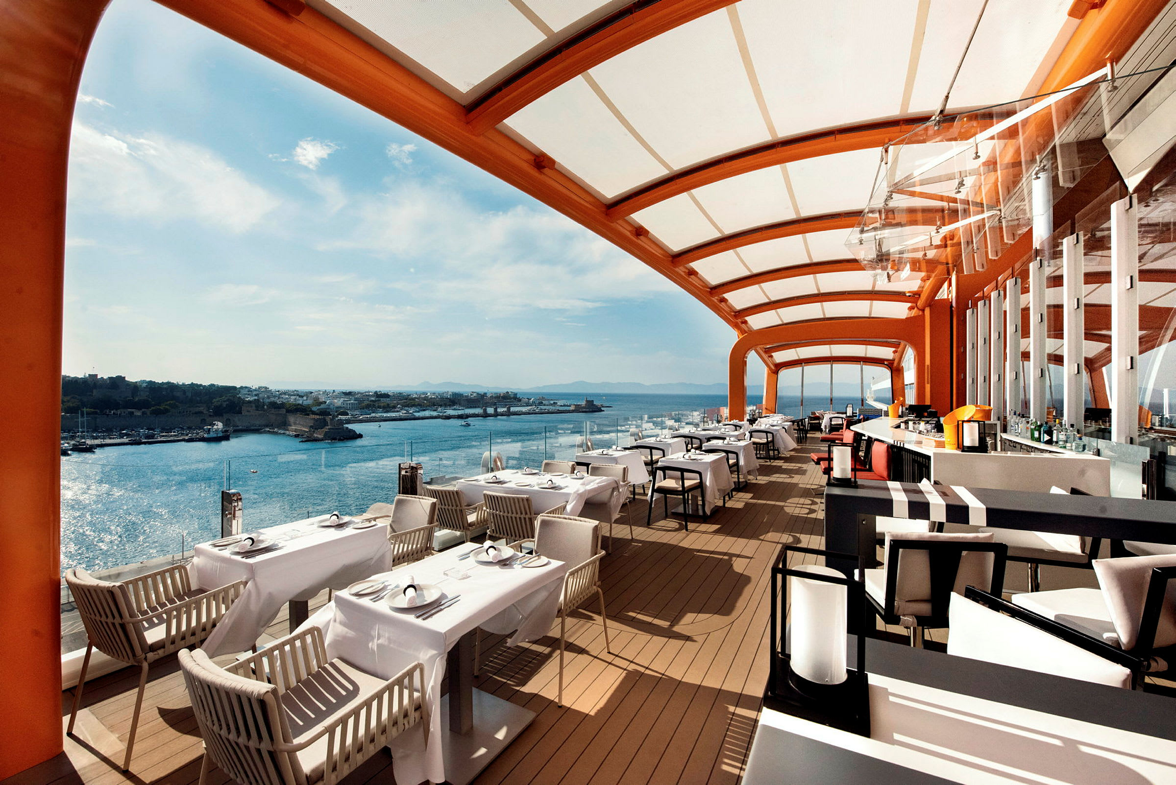 Udsigt over en restaurant med overdækket terrasse og havet i baggrunden. (AI-genereret tekst)