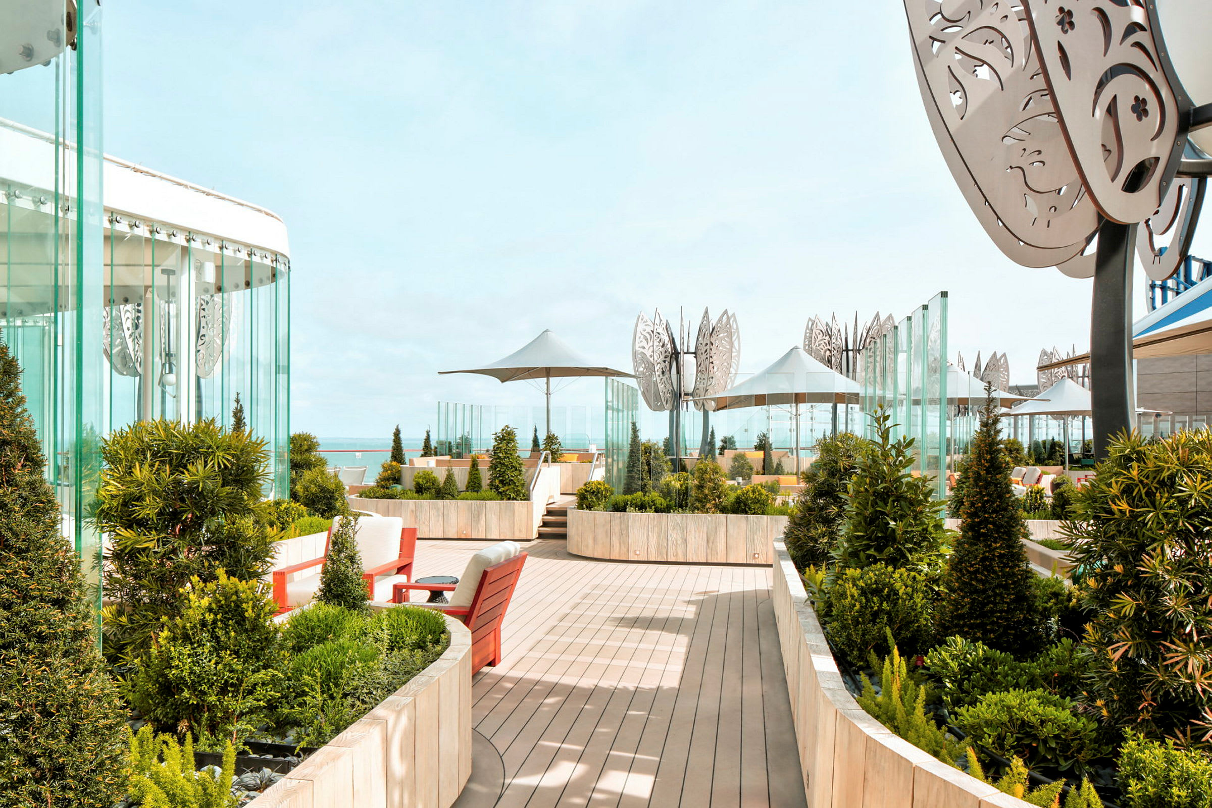 En terrasse med planter, siddeområder og udsigt til havet. (AI-genereret tekst)