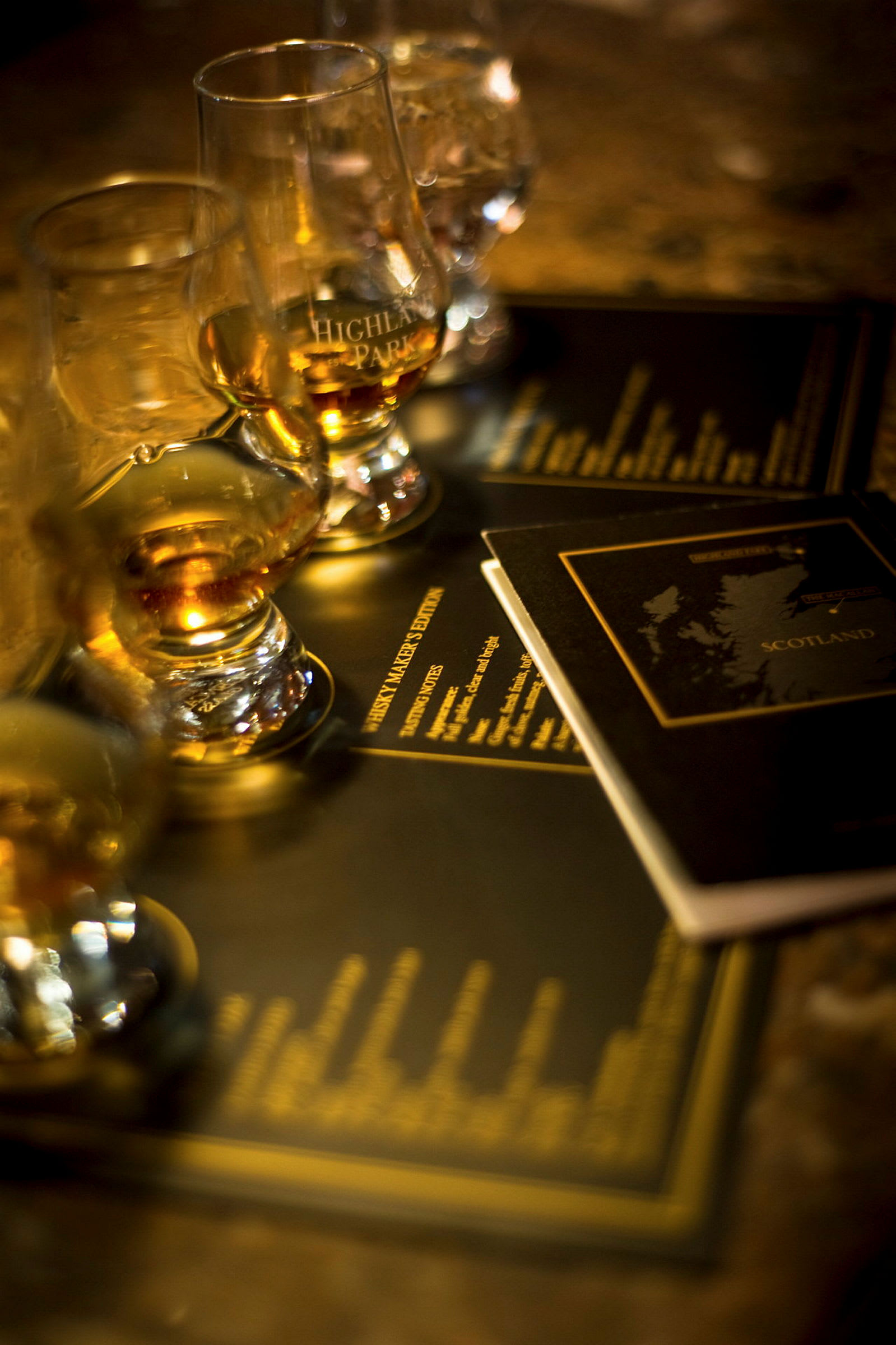 Flere glas fyldt med whisky står på et bord med brochurer i baggrunden. (AI-genereret tekst)
