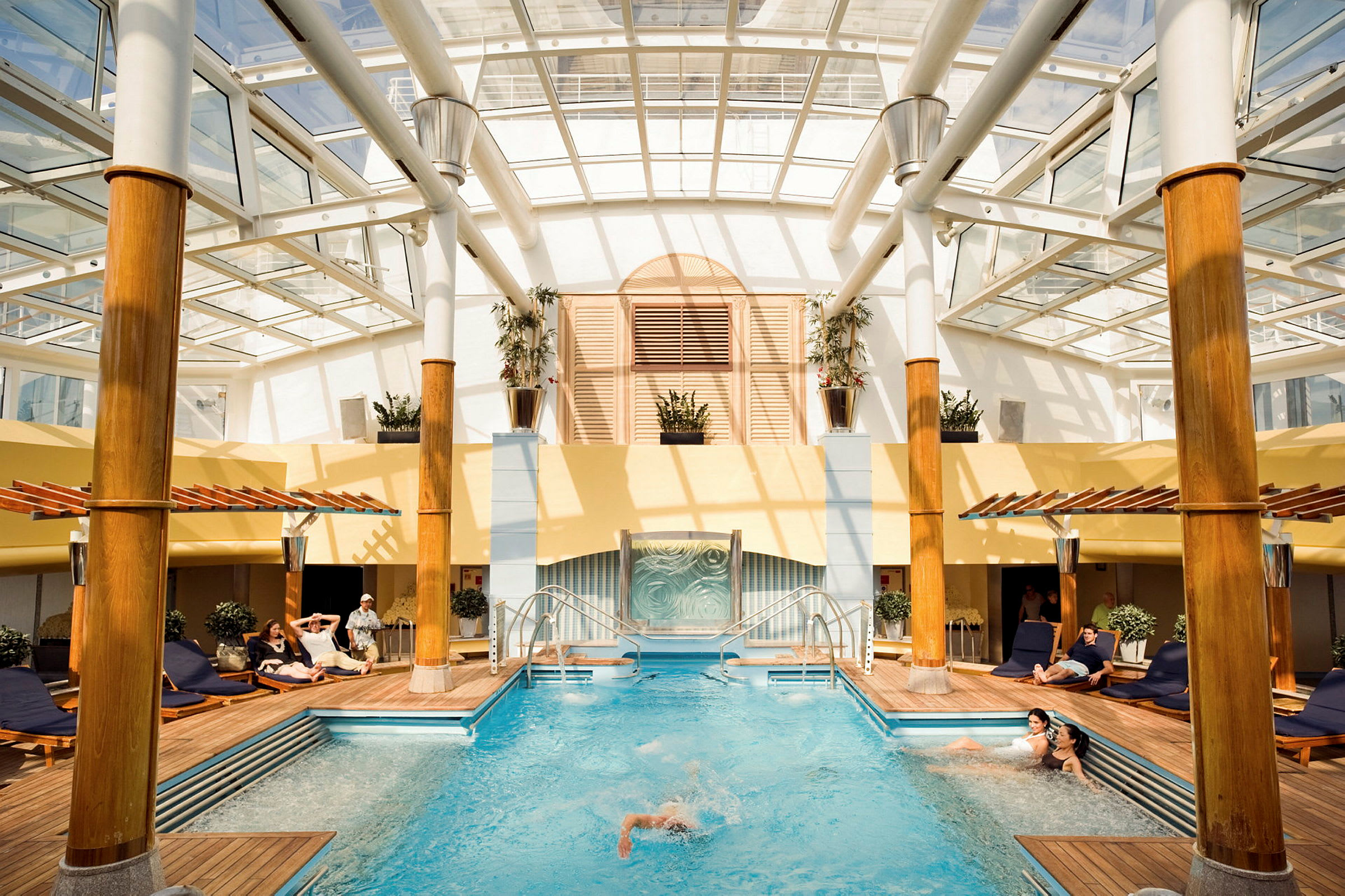 Indendørs swimmingpool med omkringliggende liggestole og træstolper. (AI-genereret tekst)