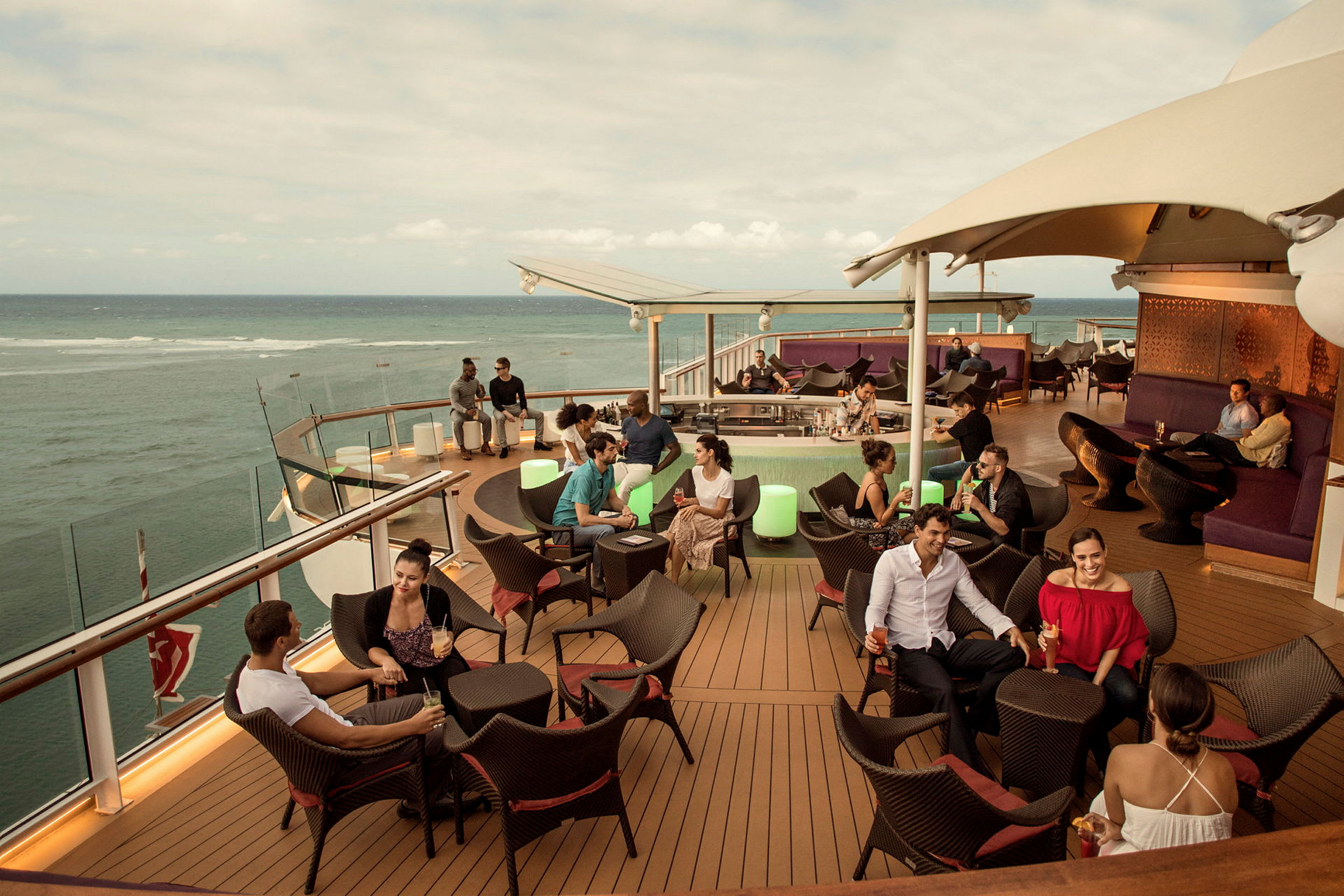 Personer sidder på en udendørs terrasse med havudsigt. (AI-genereret tekst)