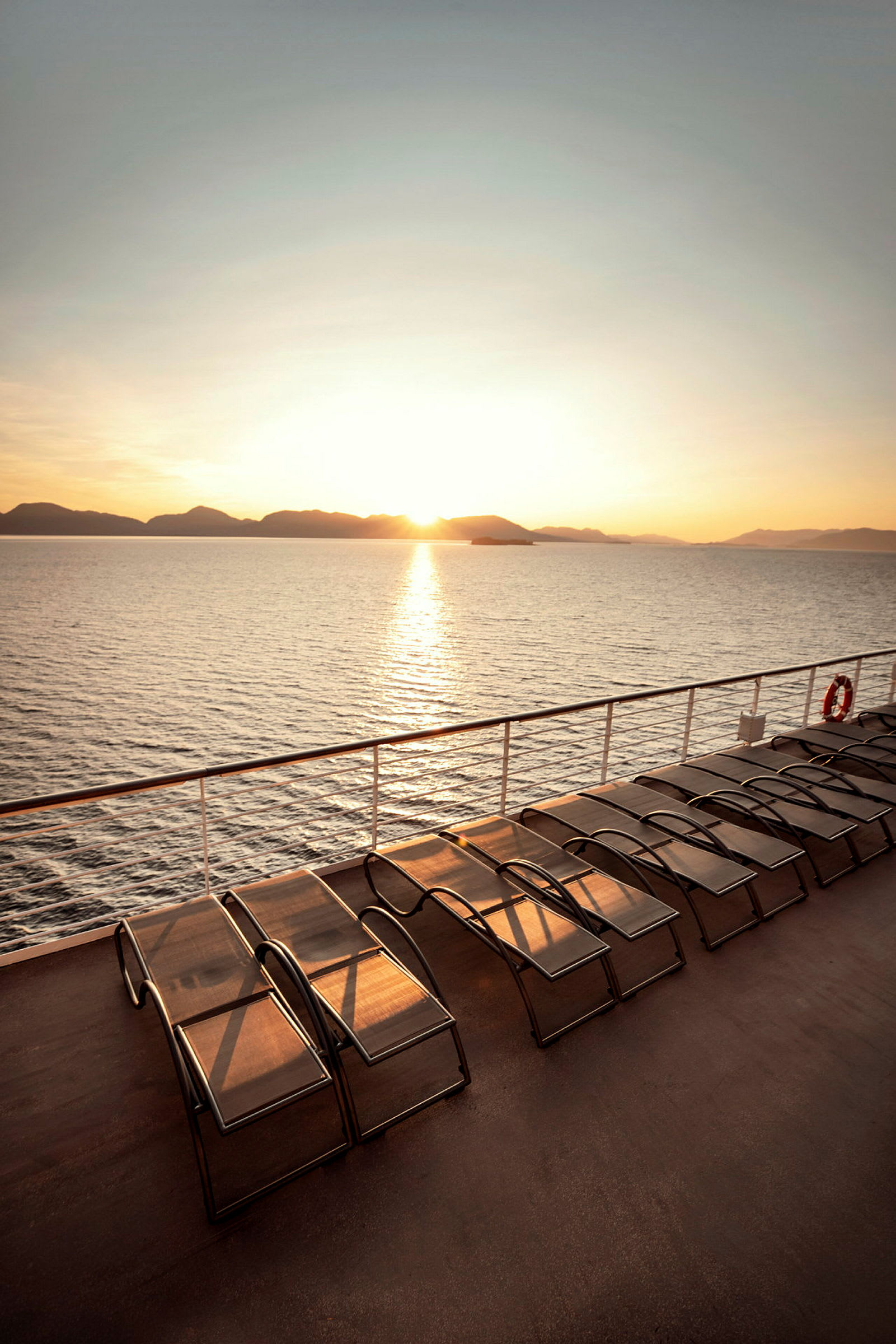 Solsenge på et skibsdæk med solnedgang over havet. (AI-genereret tekst)